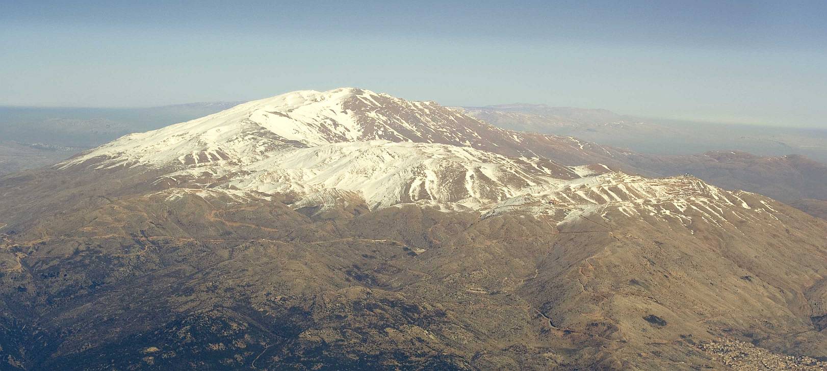 Полёт над Лыжным курортом горы Хермон, авиафотосъемка: горная вершина, покрытая снегом.